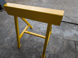 Yellow metal trestle stand on a concrete floor.